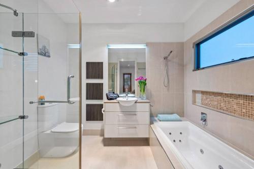 y baño con bañera, lavamanos y ducha. en Penthouse - Scarborough beach break holidays en Scarborough