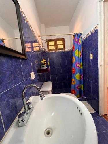 Un rinconcito en Pampatar في Pampatar: حمام مع حوض استحمام أبيض وستارة دش زرقاء