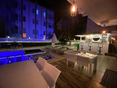 a patio with tables and chairs and a pool at night at NFK The House Hotel in Antalya
