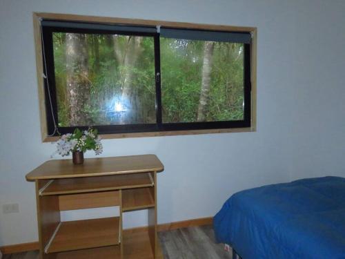 Dormitorio con ventana, cama y mesa en Cómodo chalet con tinaja rodeado de bosque nativo en Pucón