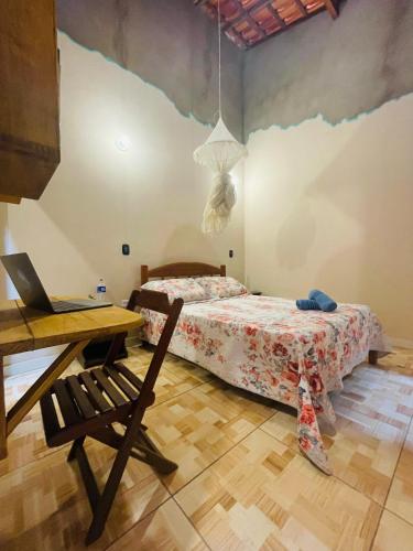 a bedroom with a bed and a desk with a laptop at Hospedagem Sabor Da Trilha in Vale do Capao