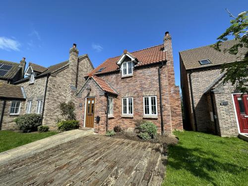 a large brick house with a red door at Gingerbread Cottage - Part of the The Bay Filey Holiday Village with pool, gym and direct beach access, pub, restaurant, tennis and meadows walks in Filey