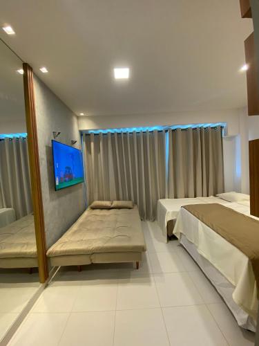 a bedroom with two beds and a flat screen tv at Mana Beach Experience Muro Alto C219 in Porto De Galinhas