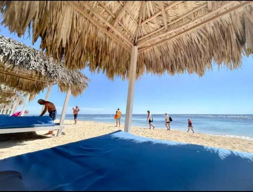eine Gruppe von Menschen am Strand mit einem Strohschirm in der Unterkunft Beautiful Home and Pool near beach , BBQ Juan Dolio metro country Club in Juan Dolio