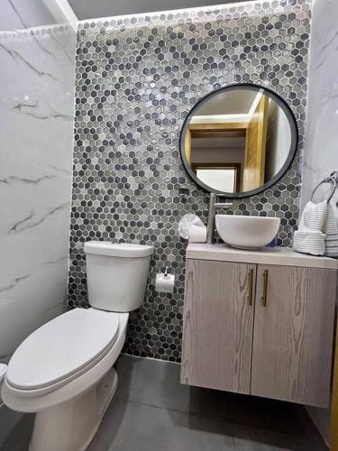a bathroom with a toilet and a mirror at Beautiful Home and Pool near beach , BBQ Juan Dolio metro country Club in Juan Dolio