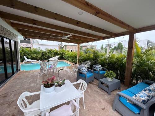 eine Terrasse mit einem weißen Tisch und Stühlen sowie einem Pool in der Unterkunft Beautiful Home and Pool near beach , BBQ Juan Dolio metro country Club in Juan Dolio