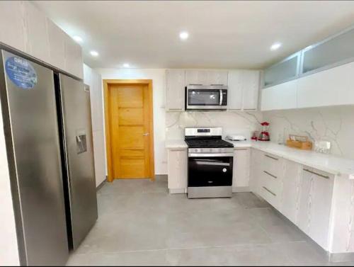 a small kitchen with a stove and a refrigerator at Beautiful Home and Pool near beach , BBQ Juan Dolio metro country Club in Juan Dolio