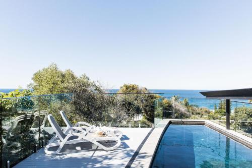 a house with a swimming pool and two chairs on the balcony at Coastal Luxury, Private Pool, Ocean Vista in Sunshine Beach