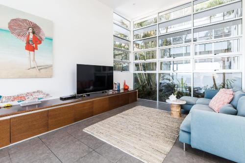 a living room with a blue couch and a tv at Coastal Luxury, Private Pool, Ocean Vista in Sunshine Beach