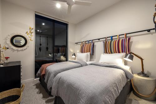 a bedroom with two beds and a mirror at Wavesong - Coast & Country in Onetangi