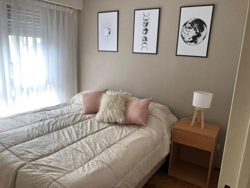 Un dormitorio con una cama con almohadas rosas y una ventana en Apartamento amoblado de 2 ambientes completo en Buenos Aires