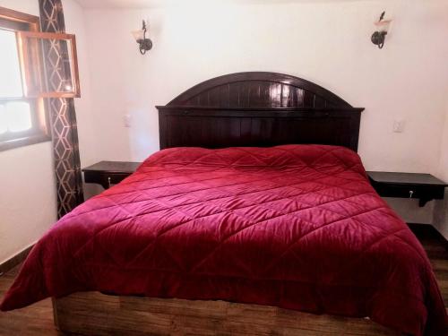 a bed with a red comforter in a bedroom at Finca Marix, Villa del Carbón in Villa del Carbón