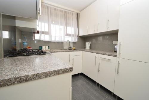 a white kitchen with a stove and white cabinets at Large private room with balcony in London