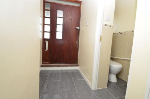 a bathroom with a toilet and a wooden door at Large private room with balcony in London