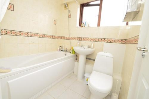 uma casa de banho com uma banheira branca, um WC e um lavatório. em Large private room with balcony em Londres