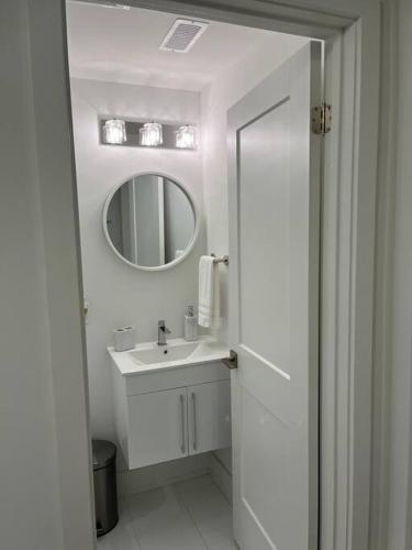 een witte badkamer met een wastafel en een spiegel bij Lovely one bedroom condo with free parking in Niagara Falls