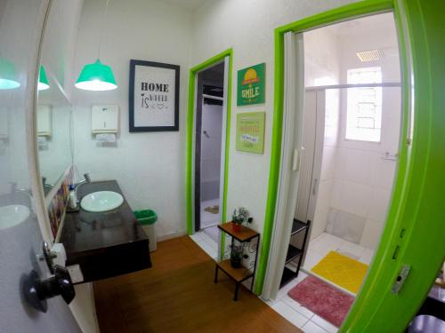 a green bathroom with a sink and a shower at Vila Rock Hostel - próximo Allianz Parque, Vila Madalena, Av Paulista, Hospital das Clínicas INCOR FMUSP in Sao Paulo