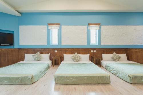 3 camas en una habitación con paredes azules en 墾丁海園別館Hai Yuan Inn, en Kenting