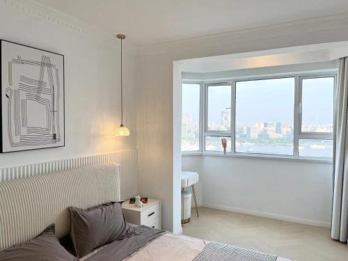a white bedroom with a bed and a window at Warm Four Bedroom Apartment with Huangpu River View in Shanghai