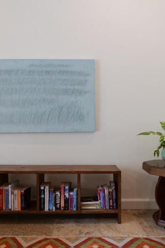 a book shelf filled with books next to a white wall at Kresna By The Sea By Kresna Hospitality in Seminyak
