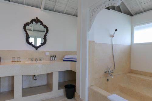 a bathroom with a tub and a sink and a mirror at Kresna By The Sea By Kresna Hospitality in Seminyak