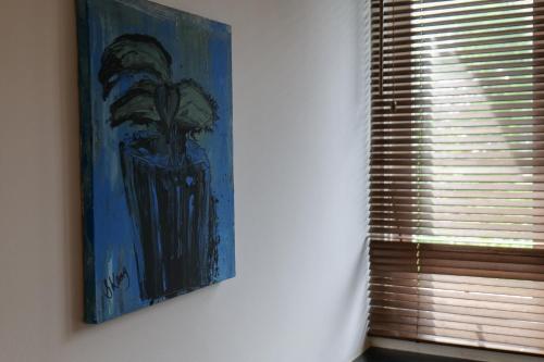 a painting hanging on a wall next to a window at Kresna By The Sea By Kresna Hospitality in Seminyak