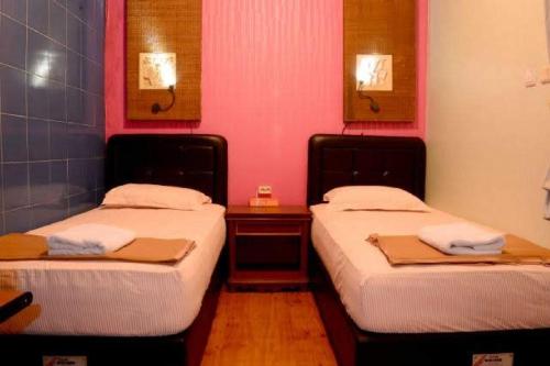 - 2 lits jumeaux dans une chambre aux murs roses dans l'établissement MOJOKERTO GUESTHOUSE, à Mojokerto