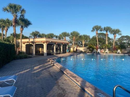 a swimming pool with palm trees and a building at Family-Friendly DIsney Getaway in Kissimmee