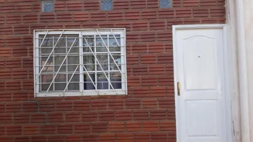 una ventana en una pared de ladrillo rojo con una puerta blanca en Rosas Blancas en Posadas