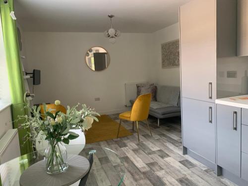 a kitchen and living room with a table and yellow chairs at Peterborough City Center One Bed apartment With Free Private Parking in Peterborough