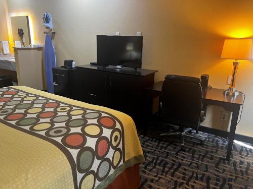 a hotel room with a bed and a desk and a television at Super 8 by Wyndham Pasadena in Pasadena