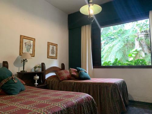 1 dormitorio con 2 camas y ventana grande en Casa com cachoeira e rio particular en Petrópolis