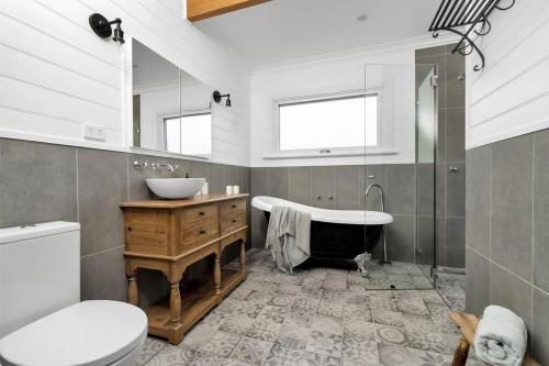 a bathroom with a sink and a tub and a toilet at Quarry Hill Cottage, 1 minute walk into Berrima. in Berrima