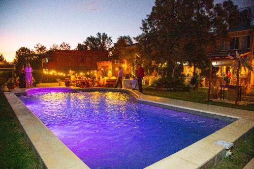 Ein Swimmingpool mit violetter Beleuchtung in einem Garten bei Nacht in der Unterkunft Hostería La María in Rosario de la Frontera
