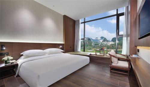 Cama blanca grande en habitación con ventana grande en Riverside Wing Hotel Guilin en Guilin