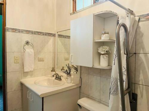 uma casa de banho branca com um lavatório e um espelho em Alojamiento Tiquicia Valley em Alajuela