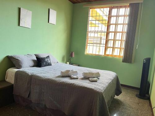 a bedroom with a bed with two towels on it at Alojamiento Tiquicia Valley in Alajuela City