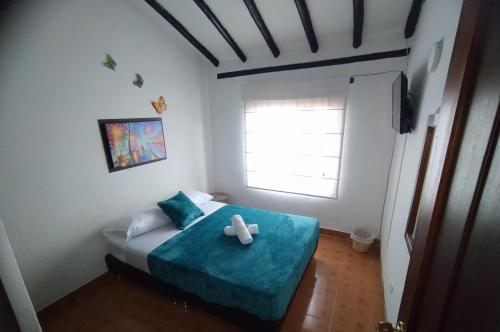 ein Schlafzimmer mit einem Bett mit einer blauen Decke und einem Fenster in der Unterkunft Hospedaje Casa Versalles in Villa de Leyva