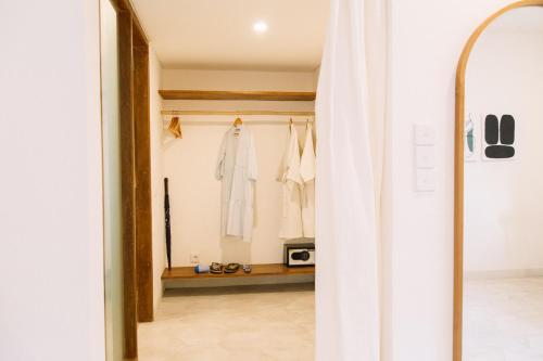 a room with a closet with a white robe at Kresna By The Sea By Kresna Hospitality in Seminyak