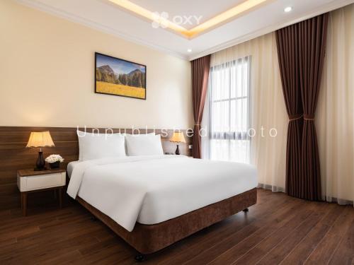 a bedroom with a large white bed and a window at Ha Long Essence Classic Hotel in Ha Long