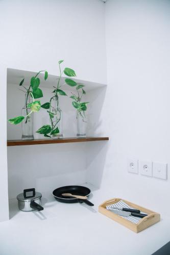 a white counter with two vases with plants on a shelf at Kresna By The Sea By Kresna Hospitality in Seminyak