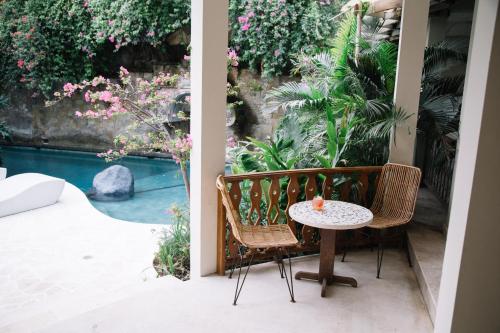 a table and chairs on a patio with a pool at Kresna By The Sea By Kresna Hospitality in Seminyak