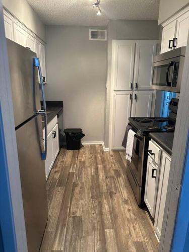 a kitchen with white cabinets and a wooden floor at Cozy 2 bedrooms by AT&T Stadium in Arlington