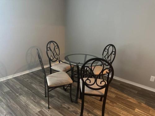 a glass table and four chairs in a room at Cozy 2 bedrooms by AT&T Stadium in Arlington