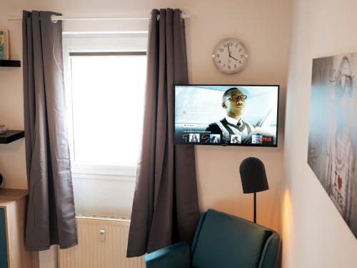 a television on a wall with a clock and a chair at Chilly Studio - Super Central in Mannheim