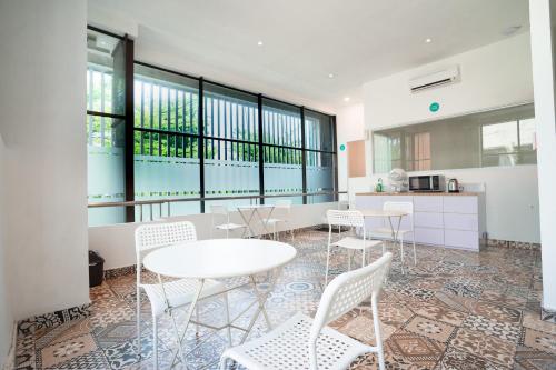 梭羅的住宿－Bobopod Slamet Riyadi, Solo，一间设有白色桌椅和窗户的用餐室