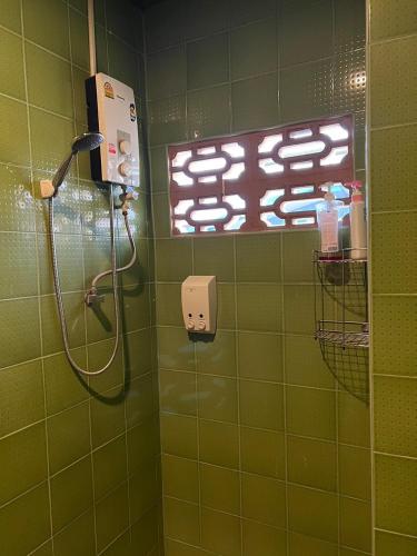 a green tiled bathroom with a shower with a phone at Blue Chang House in Bangkok
