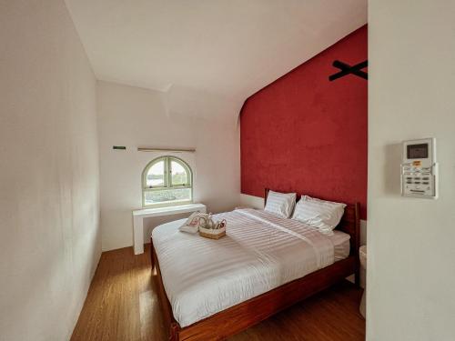 a bedroom with a large bed with a red wall at Renjana Beach House in Bira
