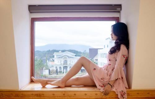 a woman sitting on a window sill in a dress at Hoàng Yến Villa Dalat in Da Lat