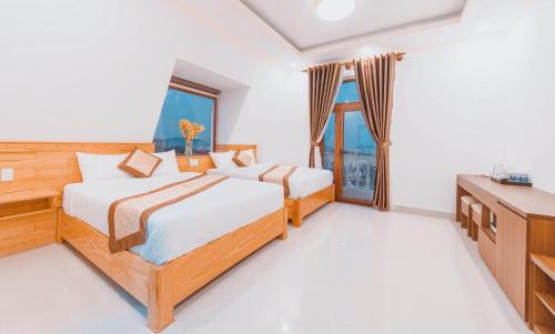 een slaapkamer met 2 bedden, een bureau en een televisie bij Hoàng Yến Villa Dalat in Da Lat